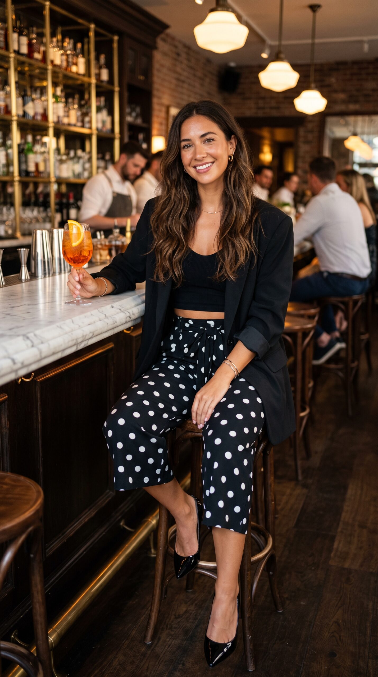 Outfit serale smart casual con pantaloni neri a pois bianchi, crop top e blazer oversize nero.