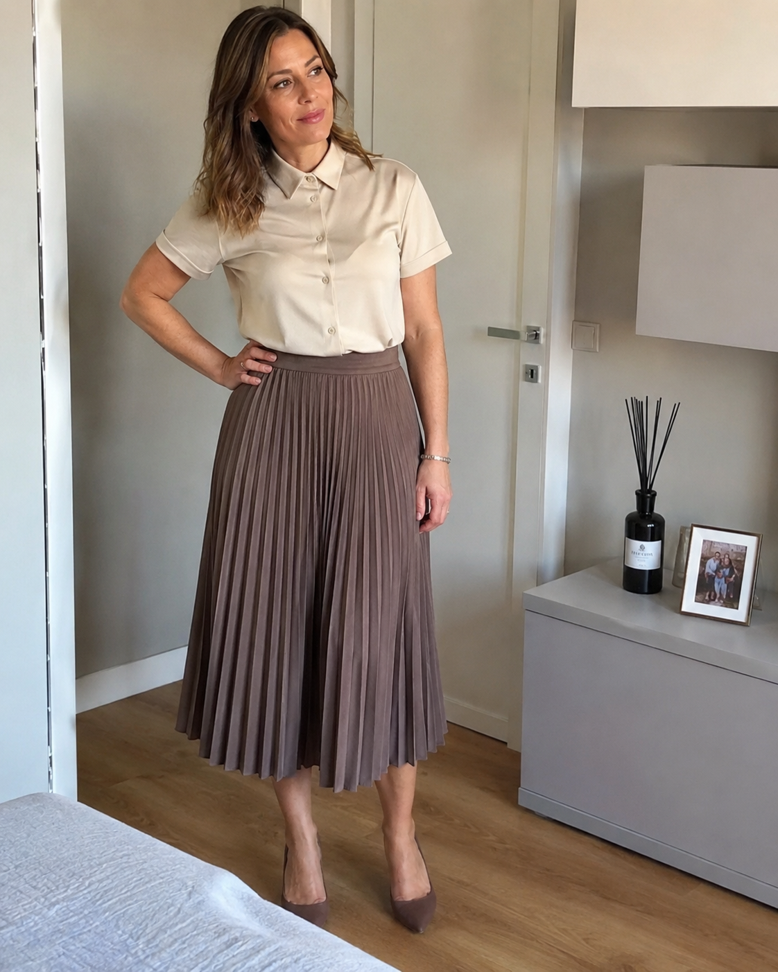 Donna di circa 40 anni con gonna midi plissettata e camicetta corta abbottonata fino in cima