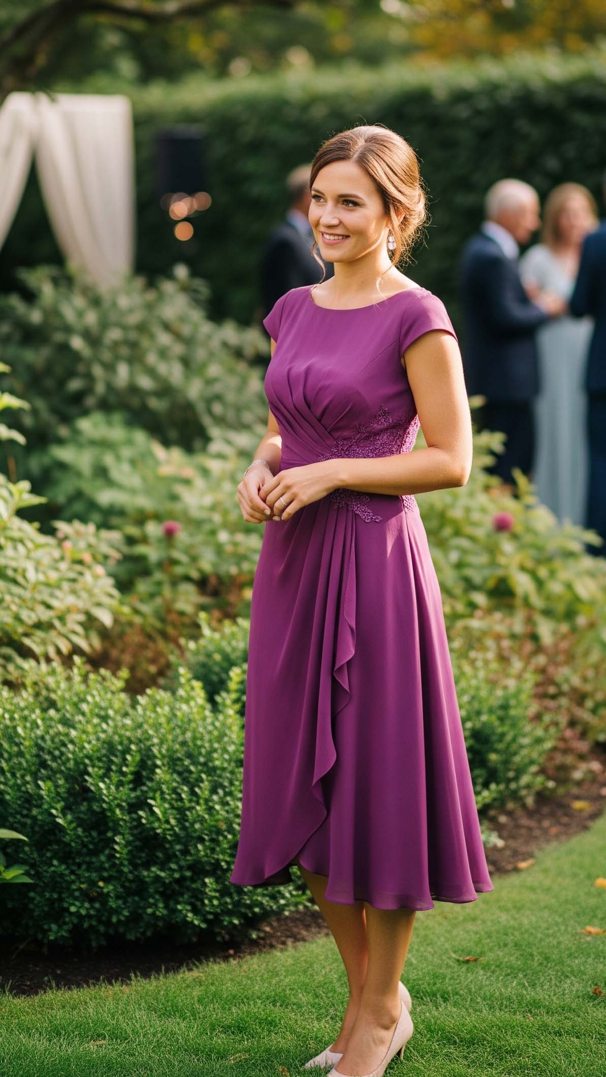 Donna sorridente con un abito al ginocchio color viola prugna, un look sofisticato per un'invitata a un matrimonio a settembre.

