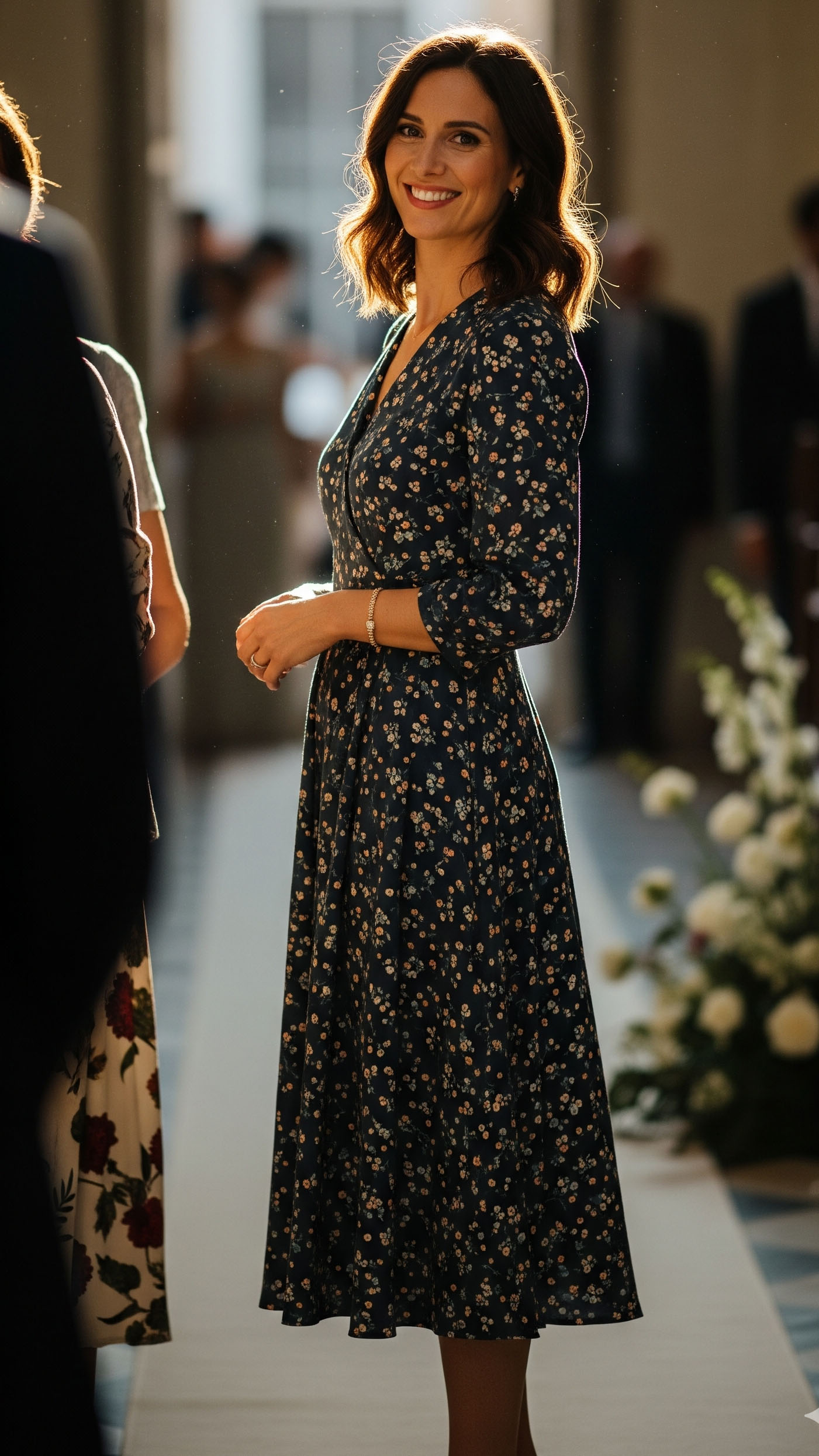 Donna con abito midi a fantasia floreale su base blu navy, look raffinato e allegro per un battesimo settembrino.