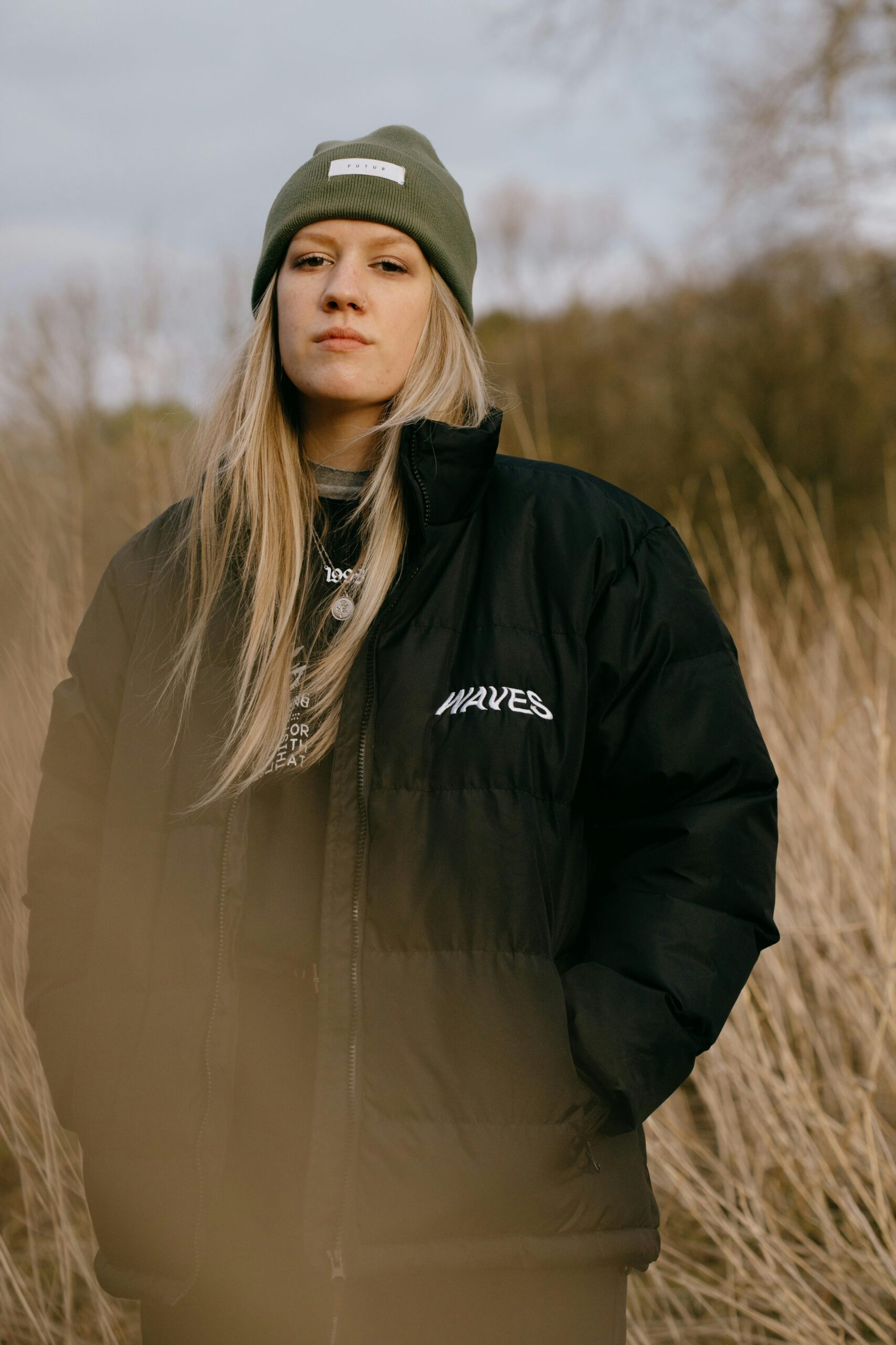 Donna con giubbotto invernale nero e berretto verde in un outfit caldo per l'inverno, fotografia outdoor naturale