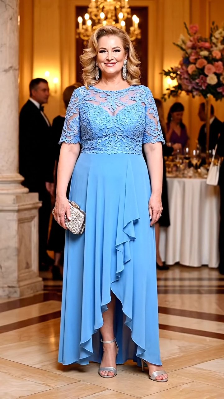 Mamma dello sposo con abito da cerimonia azzurro, corpetto in pizzo con maniche corte e gonna asimmetrica con balza, sandali argento e clutch brillante.