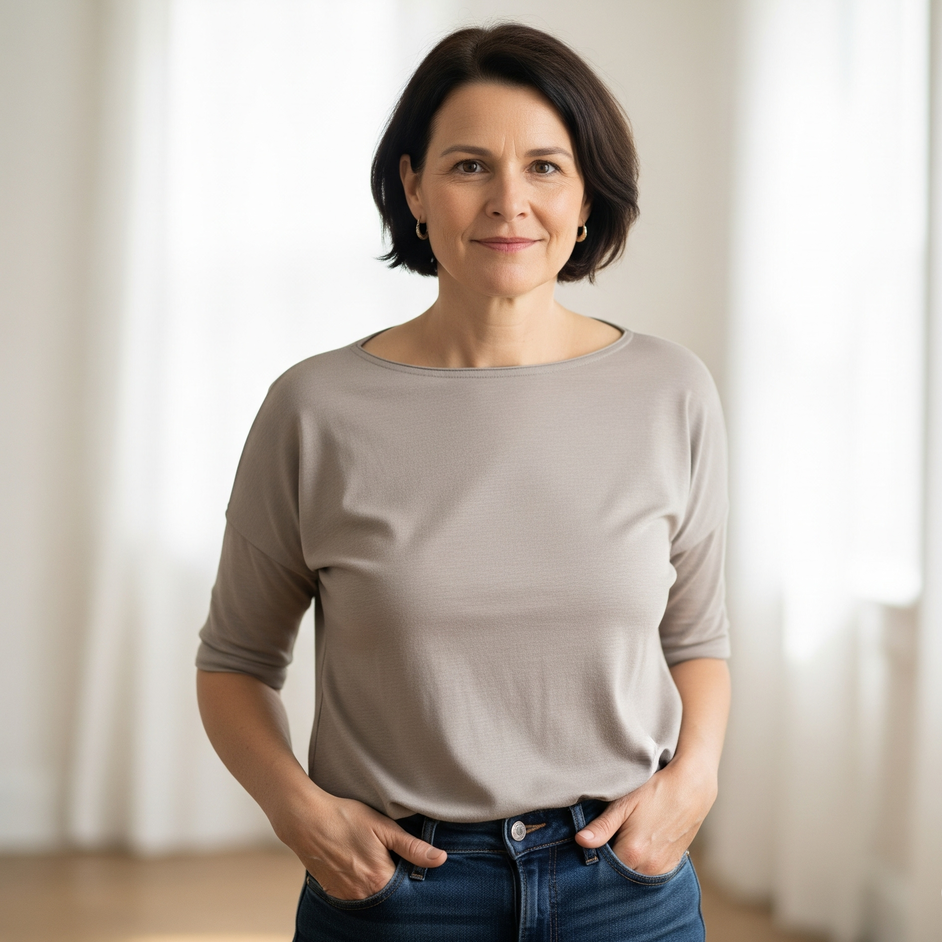 Donna di 50 anni con top neutro e jeans, esempio di look base per un guardaroba capsula over 50.

