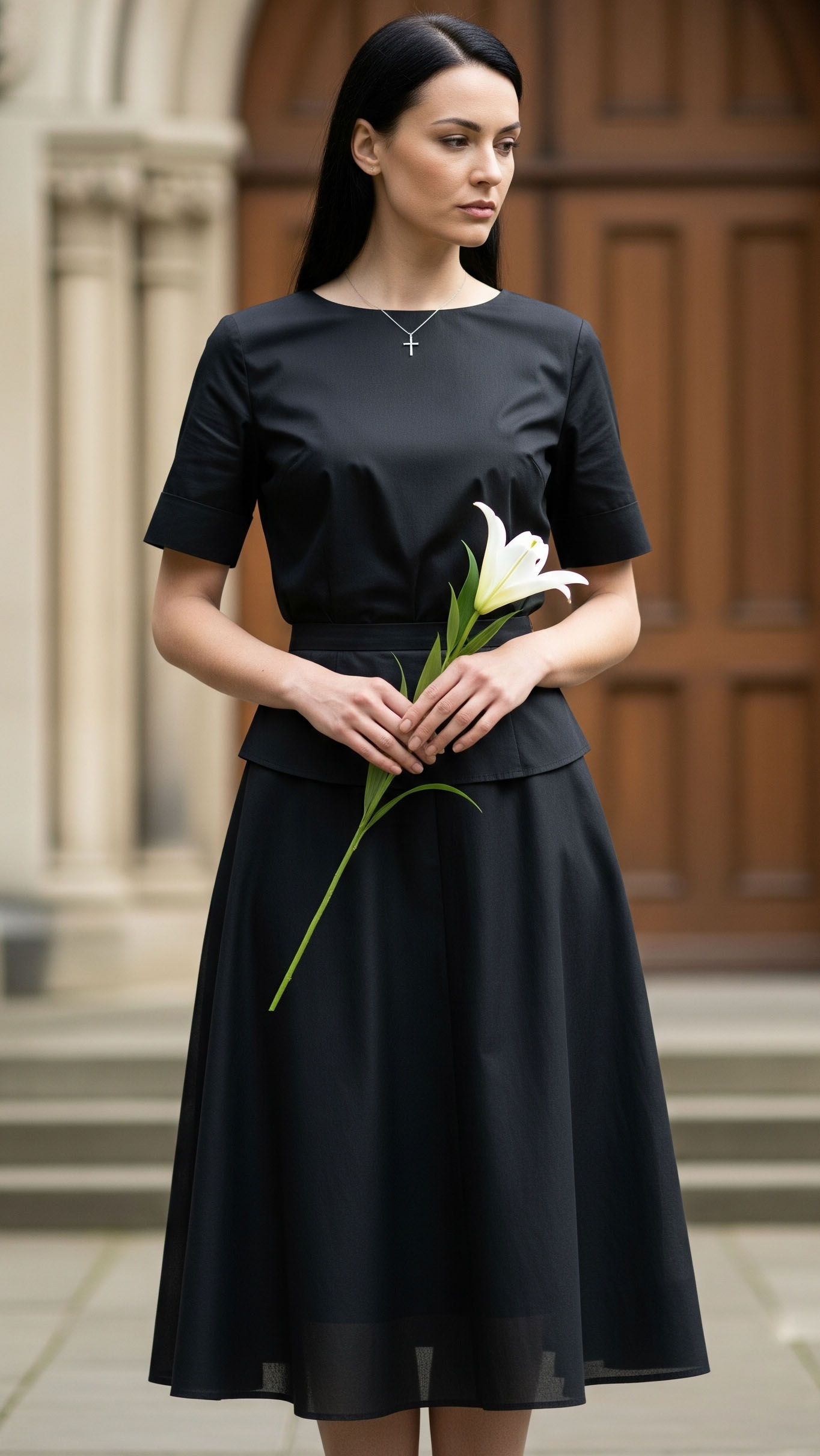 Donna a un funerale con abito nero sobrio, gonna al ginocchio e camicetta a maniche corte, look elegante e rispettoso.