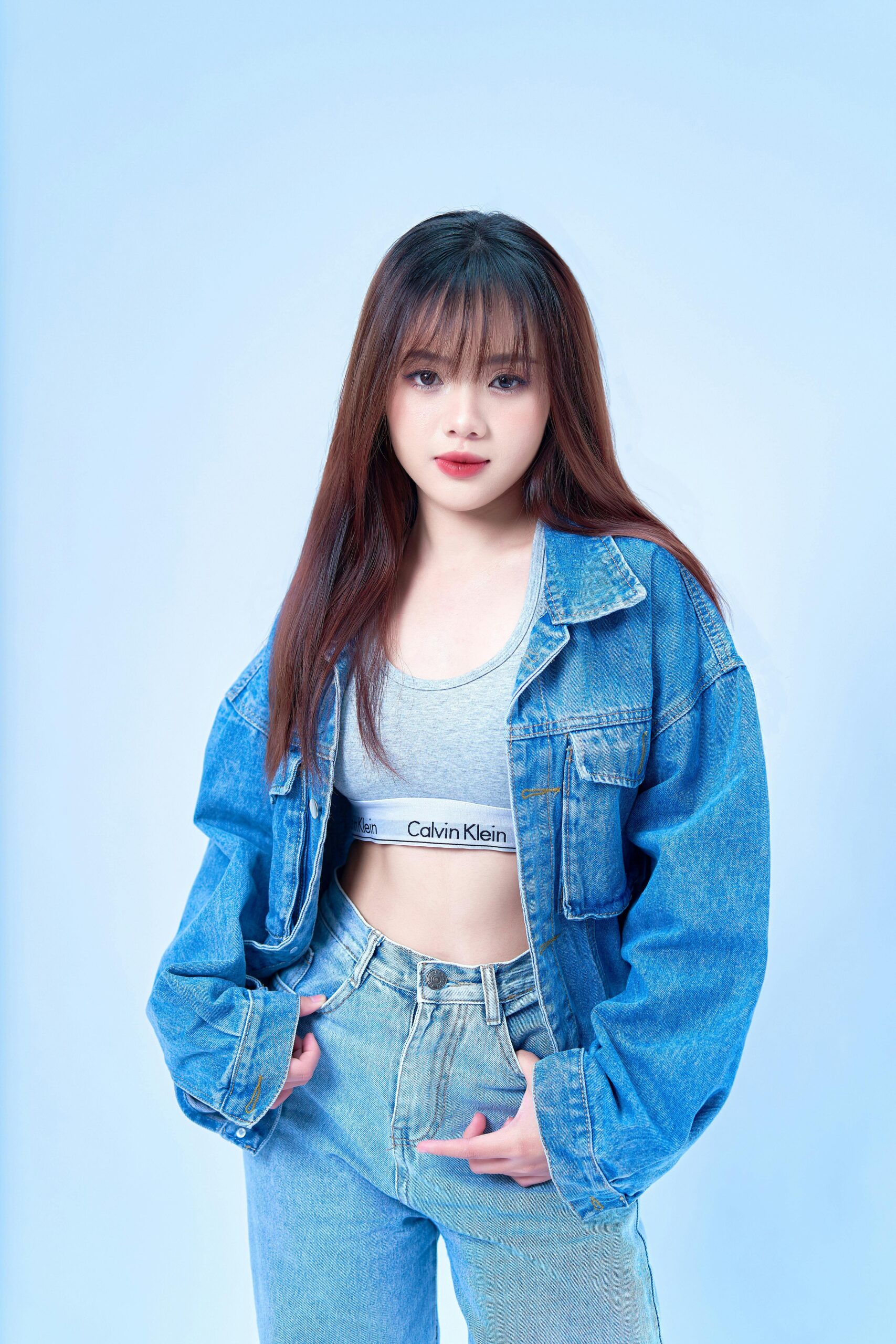 Una ragazza indossa una giacca di jeans oversize a lavaggio medio-chiaro, un top sportivo grigio e jeans abbinati, rappresentando un look casual e trendy. Perfetto per illustrare l'introduzione di un articolo sulle giacche di jeans da donna.