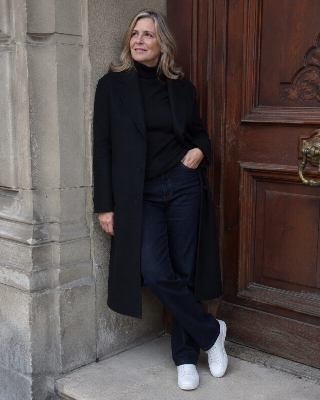 Jeans scuro dritto + dolcevita nero + cappotto lungo + sneaker bianca di pelle pulita.