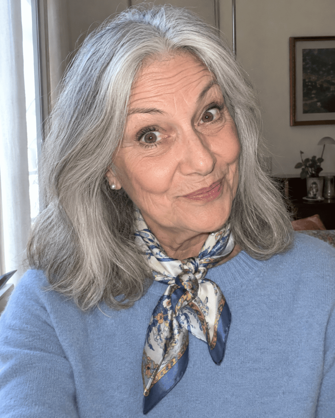 Come Vestirsi a 70 Anni: Guida Completa e Consigli Pratici 12 Donna di 70 anni con maglione azzurro polvere e foulard di seta annodato al collo
