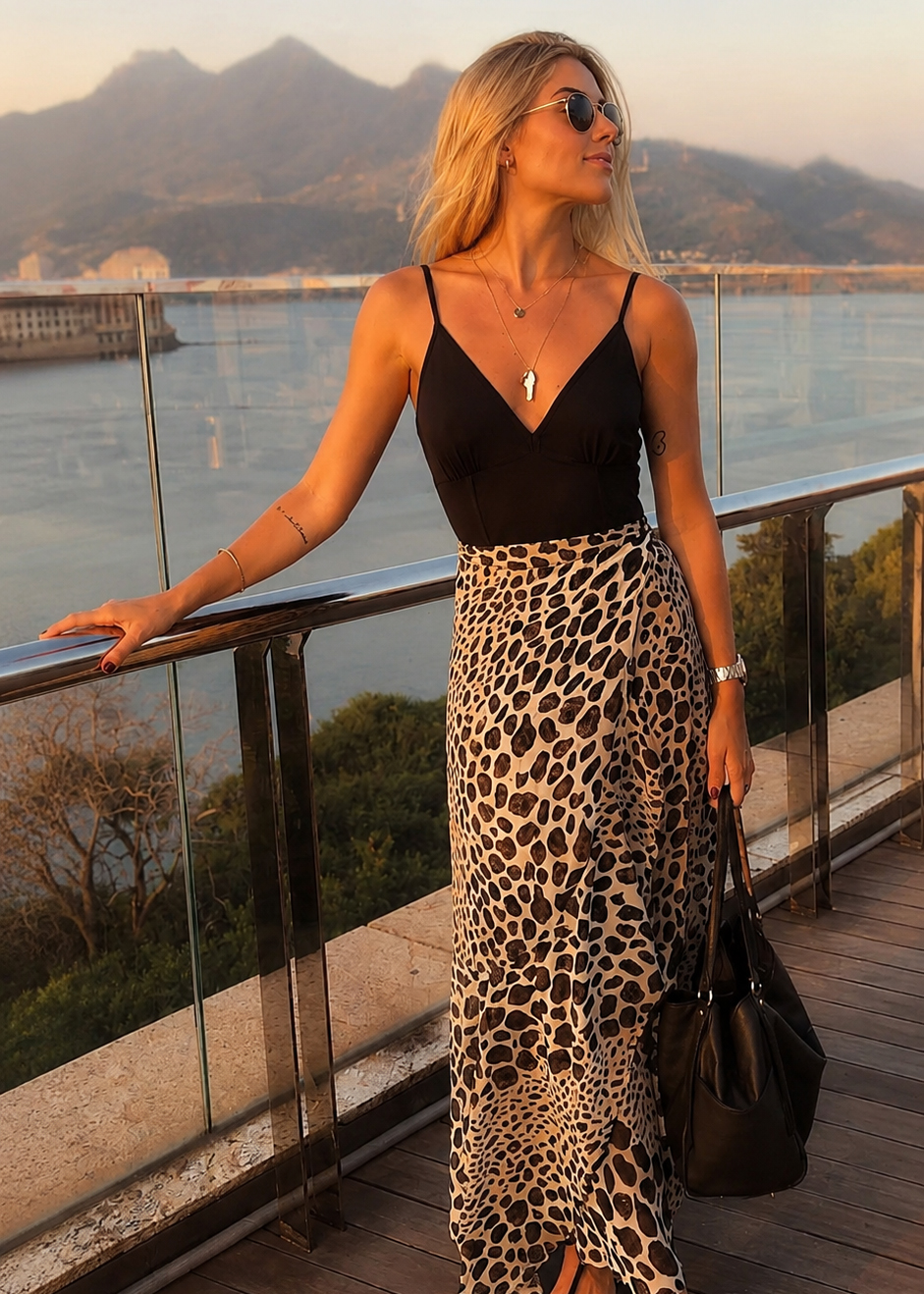 Donna con outfit estate sera 2026: body nero con spalline e gonna lunga leopardata a portafoglio per aperitivo estivo
