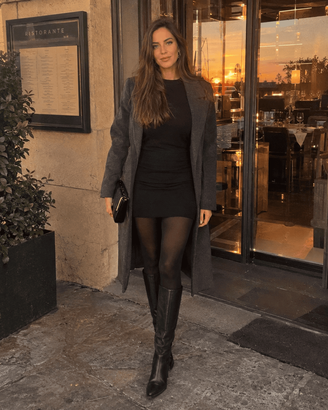 Outfit sera 12 gradi: abitino nero in maglina, collant coprenti, stivali al ginocchio e cappotto grigio lungo