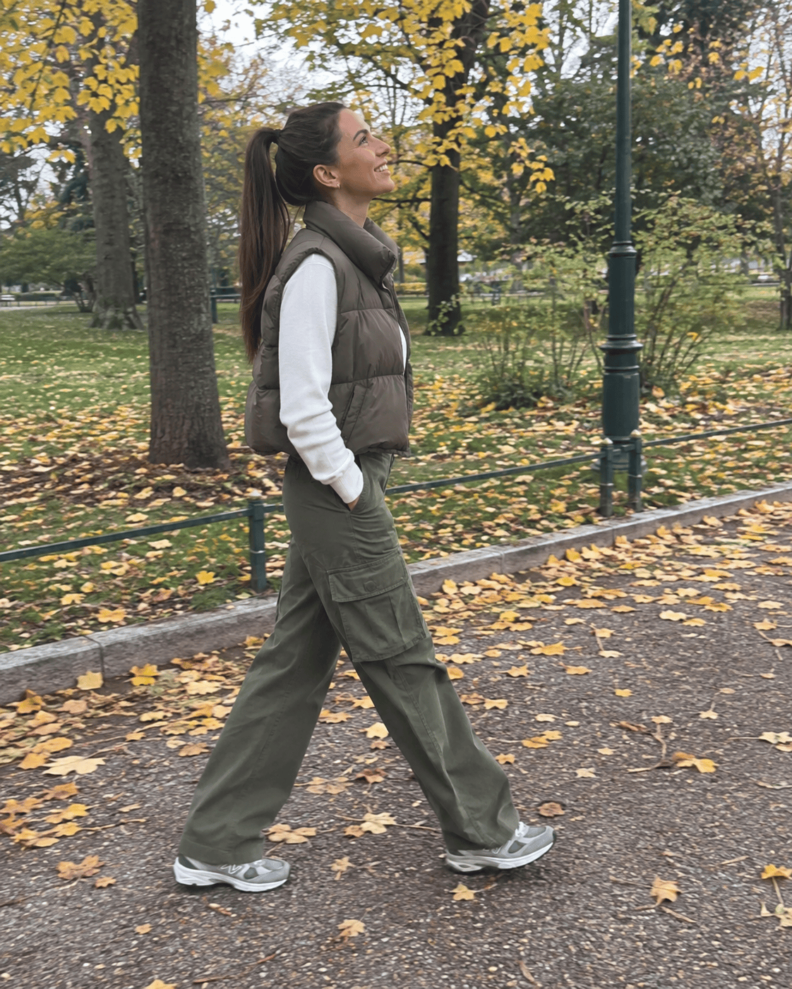 Outfit weekend 12 gradi: pantaloni cargo verde oliva, maglia bianca, gilet imbottito kaki e sneakers