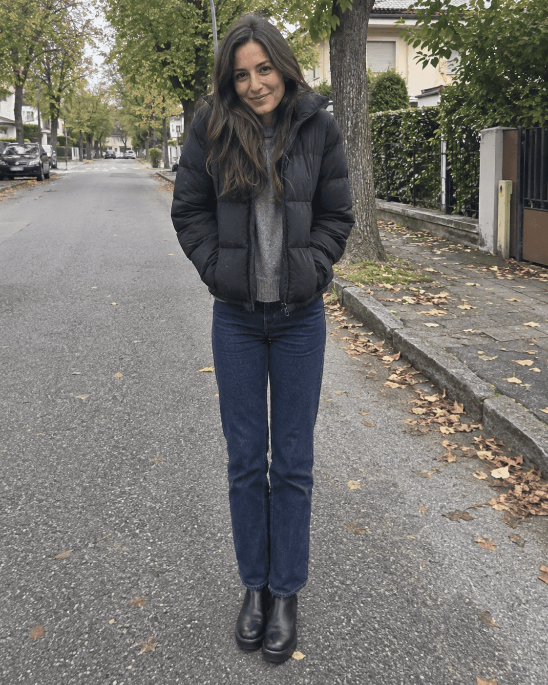 Piumino corto nero con maglione grigio, jeans blu scuro e stivaletti chelsea neri